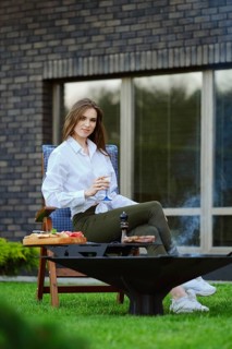 Cute young woman sits on chair with glass of lemonade on backyard