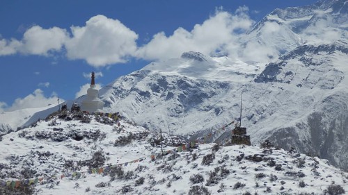 Snowy hill with stupa and prayer flags in the Himalayas, trekking at Annapurna Circuit, Manang,