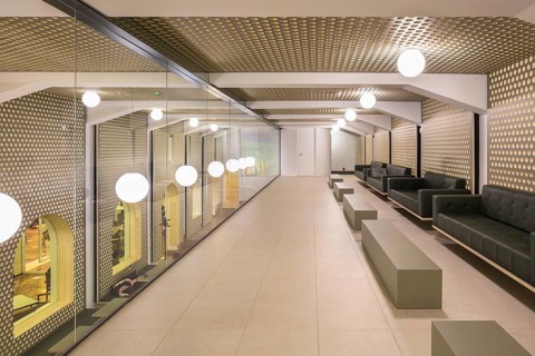 Spacious club hallway featuring a geometric ceiling and mirrored walls with round lights.
