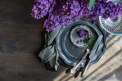 Overhead view of an elegant table setting featuring a vintage metal plate, fork, and knife. A sprig