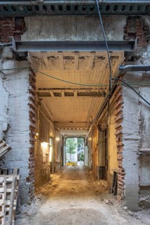 A construction site featuring a partially demolished entrance with exposed bricks and reinforced