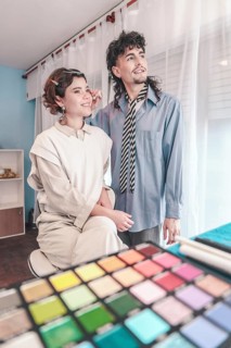 Professional makeup artist applying makeup on a beautiful young model, working together in a bright