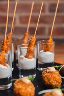 Close-up of crispy skewered appetizers artfully served in shot glasses filled with a creamy dipping