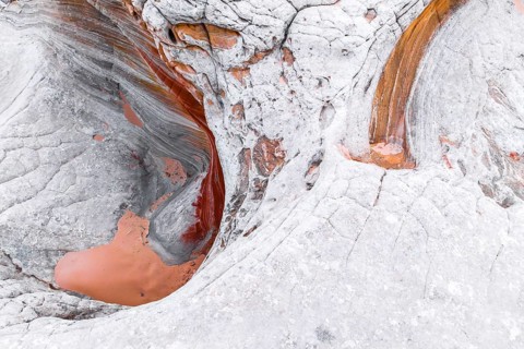 An intriguing close-up view of abstract white rocks with swirling orange and brown patterns,