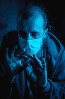 A young man wanting to leave home in the quarantine of the covid 19 one rainy night with a mask