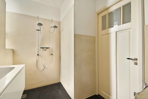 Modern bathroom featuring a minimalist shower setup with dual shower heads. The elegant cream