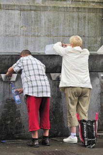 Pilgrims filling bottles with healing water at spring of the Sanctuary of Our Lady of Lourdes,