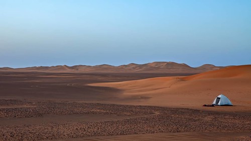 A single tent in a quiet desert at dawn with a wide view, tent camp in the Sahara desert between