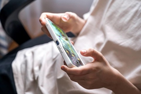 Close-up of a teenage boy playing a game on a smartphone. His focus and engagement highlight modern