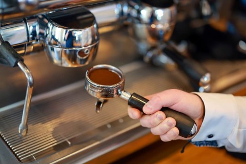 Germany - Barista prepares a coffee, hand guides a sieve carrier filled with coffee powder to the