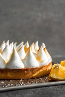 A tantalizing close up of a lemon meringue pie, featuring toasted meringue peaks on a crumbly crust