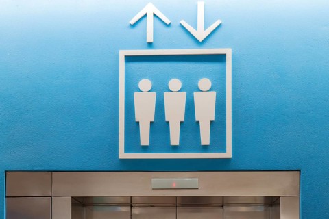 Contemporary elevator signage with up and down arrows above an entrance in a modern airport