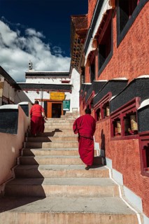 THIKSEY, INDIA, SEPTEMBER 13, 2012: Young Buddhist monks walking on stairs along prayer wheels in