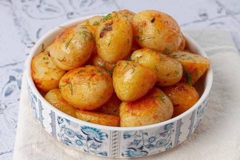 Baked new potatoes, with butter and dill, on a white plate, at home, no people