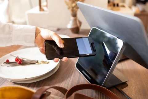A customer uses a smartphone for a contactless payment at a modern point of sale terminal in a