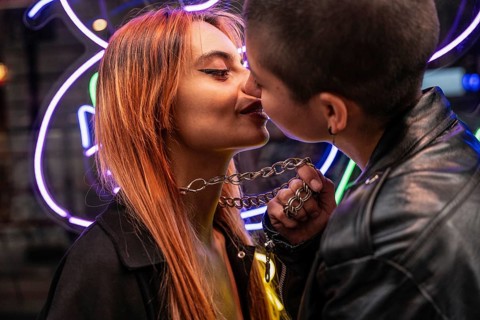 A loving lesbian couple shares a tender moment in front of neon lights, highlighting their