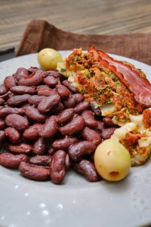 A plate features a hearty portion of red beans paired with stuffed meat that includes herbs,