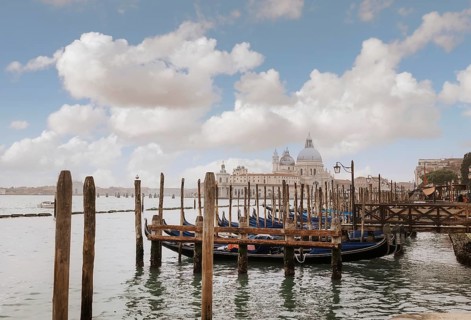 Gondolas are moored along wooden piers in Venice, Italy. The iconic Basilica di Santa Maria della