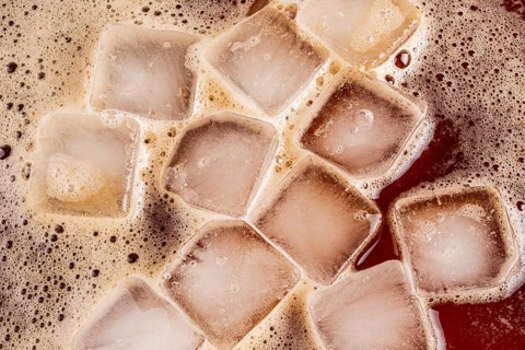 A close-up image of iced coffee with floating ice cubes. The ice cubes create a refreshing visual