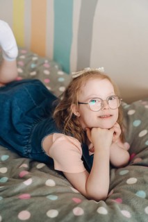 A young girl with Down syndrome joyfully engages in playtime in a colorful room. She smiles,