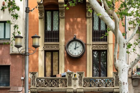 Old clock on a house facade in Figueras, Spain