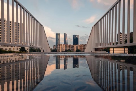 Dramatic view from a modern bridge in Madrid capturing the city skyline reflected in a puddle at
