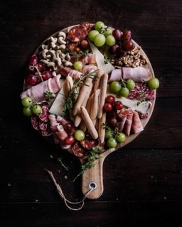 A beautifully arranged charcuterie board featuring a variety of snacks including cured meats,
