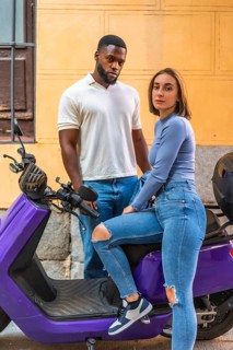 Portrait of an urban multi-ethnic couple next to motorbike scooter in the city