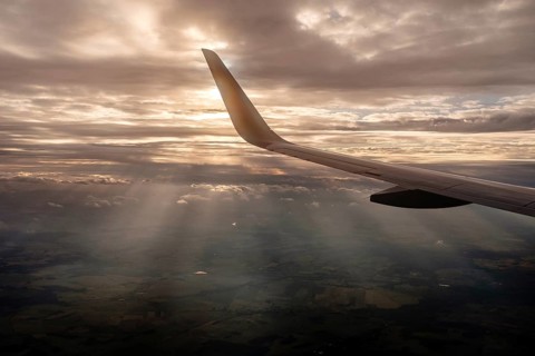 Wing of the plane during the flight with sun rays in the background