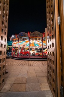 View through wooden doors onto an illuminated carousel at night, Ludwigsburg Christmas Market,