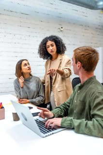 Vertical photo of an hispanic female boss scolding two employees in a coworking space