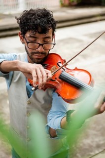 Handsome man in vest playing violin outdoors. Close up of violinist man playing a melody outdoors.