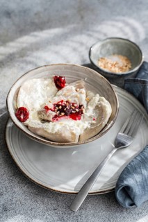 Boiled Ukrainian varenyky filled with cherry, served with a topping of sour cream and chopped nuts