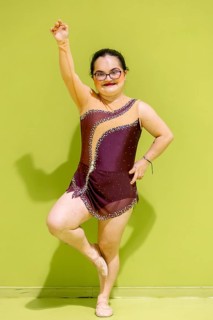 Confident disabled gymnastic wearing a sparkling outfit poses gracefully against a vibrant green
