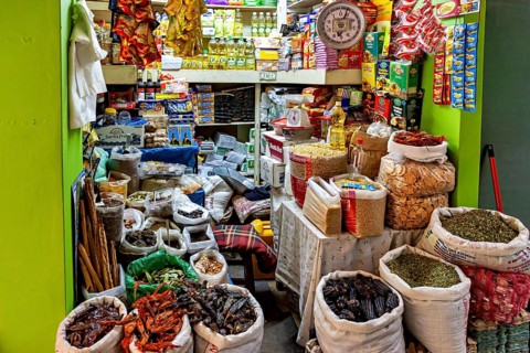 Small, well-stocked shop with bags full of spices and food in colorful packaging, The stalls in the