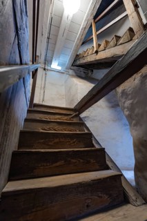 Wooden staircase in an old building with rustic atmosphere and lighting from above, Prison Museum,