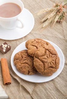 Homemade oatmeal cookies with a cup of cocoa on a linen textile and white wooden background. side