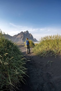 Tourist on a sand dune, Black beach with volcanic sand, Sand beach, Dunes with grass, Stokksnes