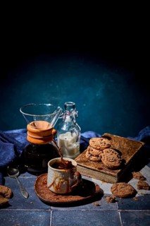 A cozy setting featuring a splash of fresh coffee in a ceramic mug, with a stack of chocolate
