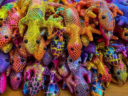 Vibrant, multicolored fabric lizard souvenirs on display at a bustling Thai market. The intricately