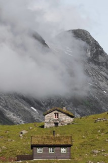 Idyllic cabins amidst green hills and foggy mountains in Norway, offering a picturesque view
