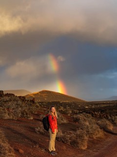 A hiker in Timanfaya National Park, Lanzarote, stands smiling against a dramatic landscape with a