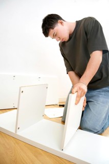 Man carefully assembling new furniture pieces in a well-lit room, focused on fitting together white