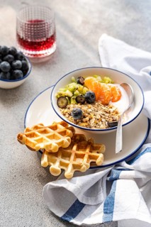 A nutritious breakfast bowl with yogurt, granola, fresh kiwi, blueberries, and tangerine slices.
