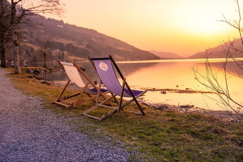 Two deckchairs stand on a gravel path on the lakeside at sunset, Großer Alpsee, Immenstadt im