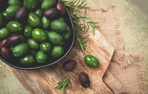 Chalkidiki olives, classic Greek green olives, in a bowl on a cutting board, top view, without