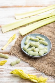 Jelly celery candies on white wooden background and linen textile. close up, side view