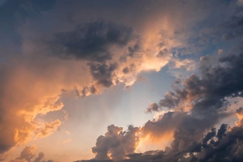A breathtaking view of a dramatic sunset sky filled with vibrant golden clouds. The warm colors