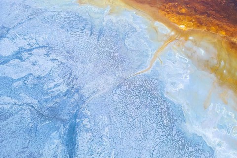 Aerial view showcasing vibrant geological formations with a striking contrast of blue and orange