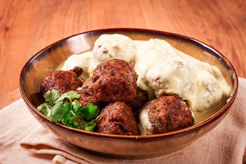 Swedish meatballs in cream sauce, plate on a wooden table, homemade, no people